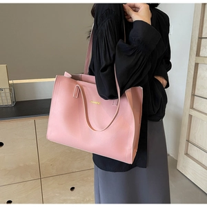 Detailed view of pink leather tote bag featuring gold metallic logo and long handles