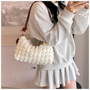 Detail of white popcorn fabric tote bag with brown leather strap and knot accent