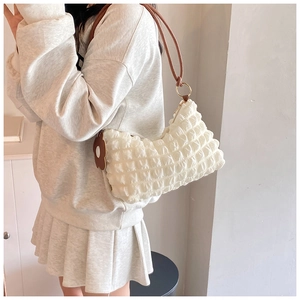 Detail of white bubble texture underarm bag with brown strap and floral charm on model