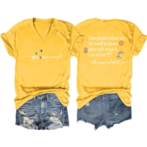 Detail view of yellow V-neck T-shirt with motivational text and distressed denim shorts