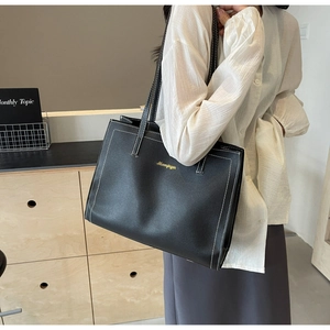 Détail du grand sac cabas noir en cuir synthétique avec des surpiqûres blanches contrastées