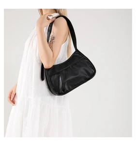 Side view of a black matte leather underarm bag with natural pleats and slender strap