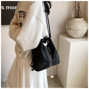 Detail of black drawstring bucket bag with silver butterfly and pearl chain ornaments
