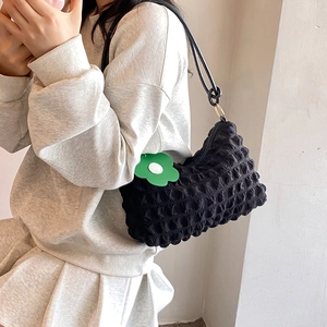 Fashionable black bubble textured hobo bag with a green floral pendant on shoulder