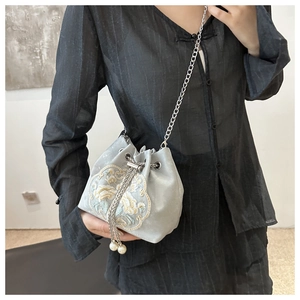 Detail of light gray velvet bucket bag with floral embroidery and pearl drawstring