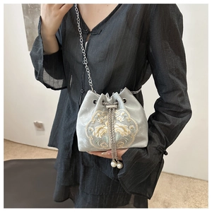 Close-up of golden floral embroidery and pearl drawstring on velvet bucket bag