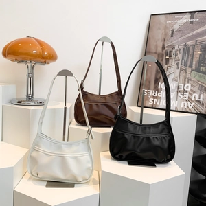 Three minimalist pleated crescent moon bags in white, brown and black with adjustable straps