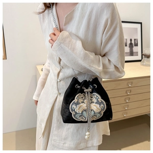 Détail de broderie florale sur sac seau en velours noir avec bandoulière chaîne et perle