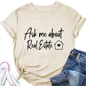 Dettaglio della t-shirt beige con testo 'Ask me about Real Estate' e icona della casa