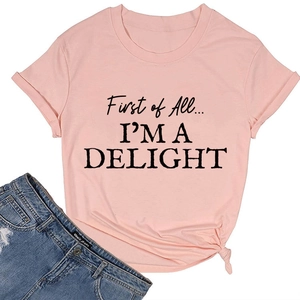 Flat lay of a pink crew neck T-shirt with 'First of All... I'M A DELIGHT' black slogan print