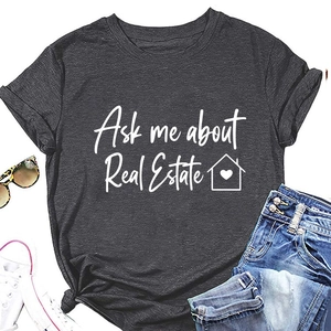 Dettaglio maglietta grigio scuro con scritta bianca 'Ask me about Real Estate' e icona