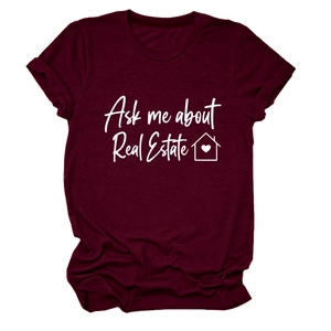 Dettaglio di una maglietta bordeaux con lo slogan Ask me about Real Estate e l'icona della casa