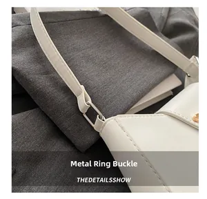 Détail des boucles en métal argenté et de la bandoulière en cuir blanc du sac à main