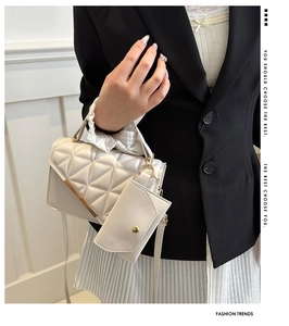 Detail of white quilted crossbody bag with golden metal trim and matching mini pouch accessory