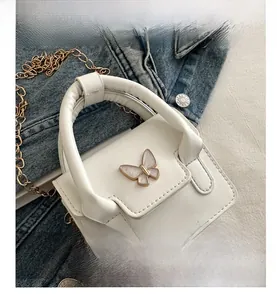 Detail of white PU mini bag with gold chain strap and pearl butterfly hardware