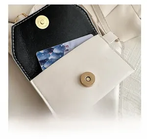 Close-up of mini contrast leather charm bag with golden magnetic snap and interior detail
