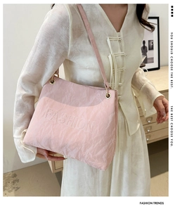 Detailed texture of pink pleated shoulder bag with FASHION embossed lettering and slim strap