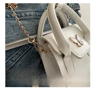 Detail of white PU leather mini bag with decorative metal butterfly and gold chain hook