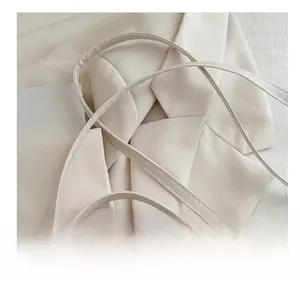 Detail of cream quilted handbag featuring slim double straps and gold metal hardware logo