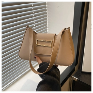 Detail of beige faux leather baguette bag featuring a gold hollow metal buckle closure