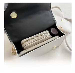 Detail view of white leather crossbody bag interior showing phone and wallet capacity