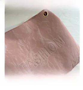 Detail of pink embossed leather tote bag with FASHION lettering and gold metal eyelet