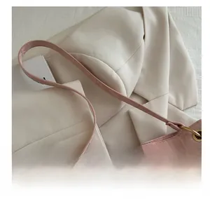 Close-up of pink patent leather tote bag with pleated texture and gold hardware detail