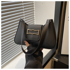 Detail of a black leather underarm bag featuring a gold wave buckle and a flap closure