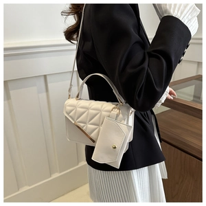 Close-up of white quilted leather crossbody bag with gold metal trim and mini charm