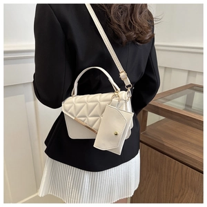 Detail of cream quilted crossbody bag set with gold trim and adjustable strap on model