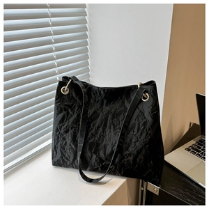 Detail of black pleated tote bag showing FASHION logo and gold metal ring hardware