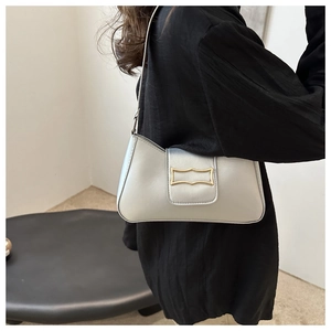 Detailed close-up of a silver textured handbag featuring a unique gold wave-shaped buckle