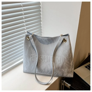 Detail of light gray tote bag featuring crinkled texture and FASHION embossed logo