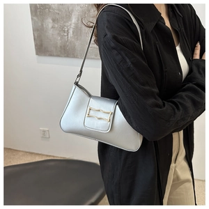 Détail du sac croissant argenté avec une boucle décorative dorée en forme de vague