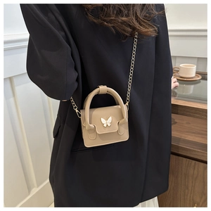 Detail of ballet style mini handbag with white butterfly buckle and golden chain strap