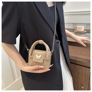 Chic khaki mini crossbody bag with butterfly hardware and gold chain shown in lifestyle setting