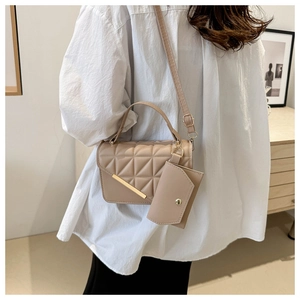 Detail of apricot quilted crossbody bag featuring a gold buckle and mini pouch