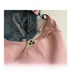 Close-up of pink nylon crossbody bag with front zipper pocket and adjustable strap