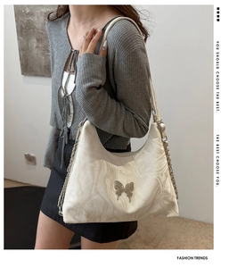 Detail of marble pattern shoulder bag with silver butterfly charm and chain strap
