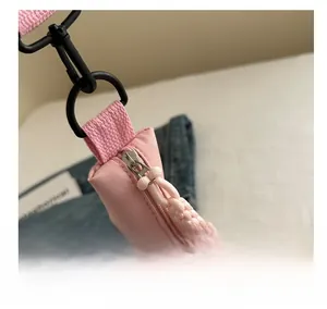 Macro detail of smooth zipper and black matte metal hook on a pink crossbody bag