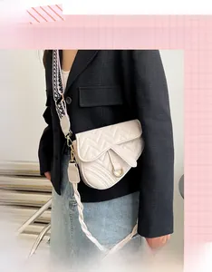 Detail of cream saddle bag with V-shaped quilting and wide woven strap on a model
