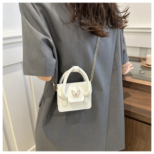 Detail showing white leather mini bag with sparkling butterfly lock and gold chain strap