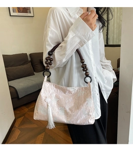 Detail of pink jacquard fabric handbag featuring wood bead handle and long white silk tassel