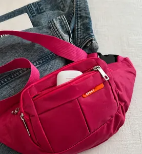 Detalle de la riñonera rosa de lona con múltiples cremalleras y correa ajustable