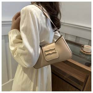 Detail of elegant apricot underarm bag with matte gold buckle worn on the shoulder