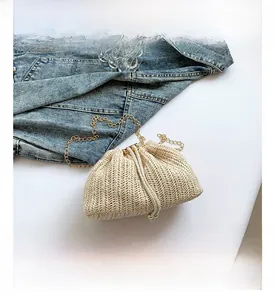 Detail shot of beige woven bucket bag with drawstring closure and golden chain strap