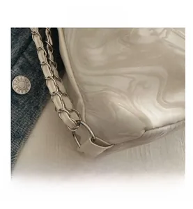 Detailed close-up of water ripple texture on beige leather tote bag with chain strap
