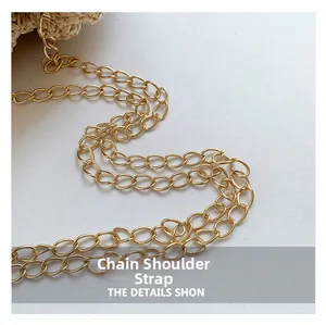 Close-up of golden metal chain strap with oval links on woven straw shoulder bag