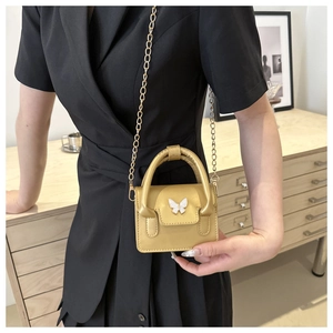 Macro shot of gold metallic mini bag featuring white butterfly hardware and chain strap