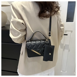 Detail of black quilted crossbody bag with gold hardware and small envelope pouch